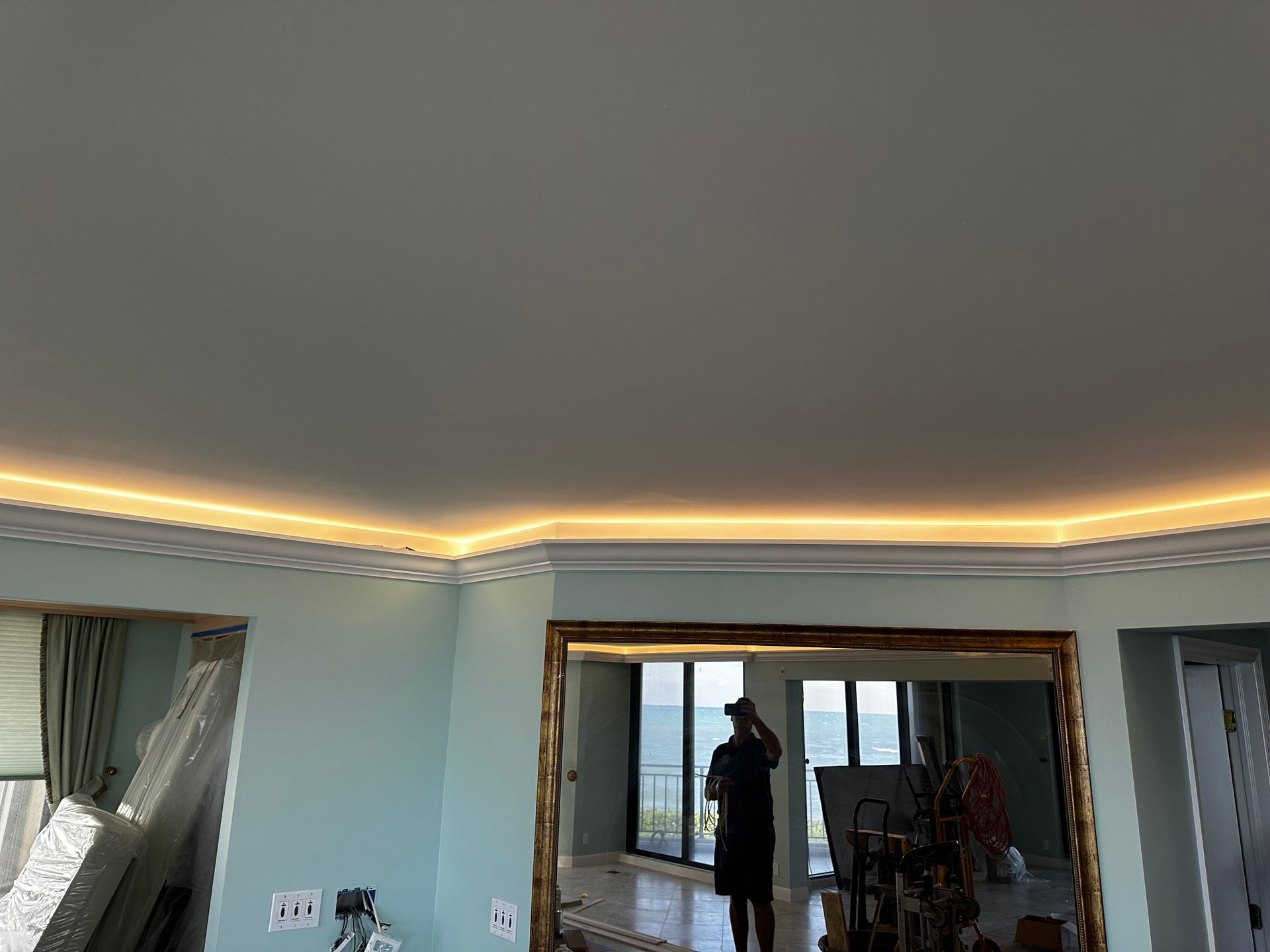 A man is standing in front of a large mirror in a living room.