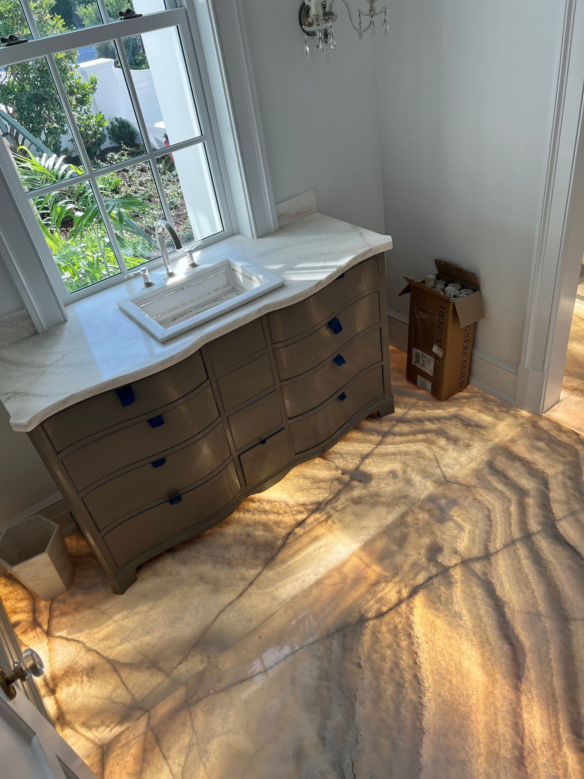 A bathroom with a sink , dresser , and window.