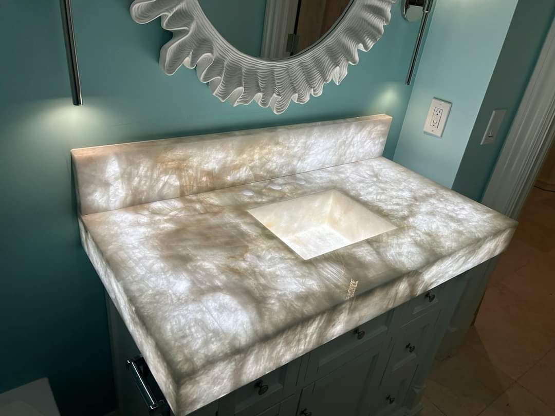 A bathroom sink with a lighted counter top and a mirror.