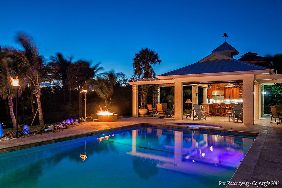 A large swimming pool with a gazebo in the background at night