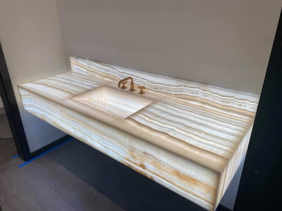 A bathroom sink with a marble counter top and a faucet.