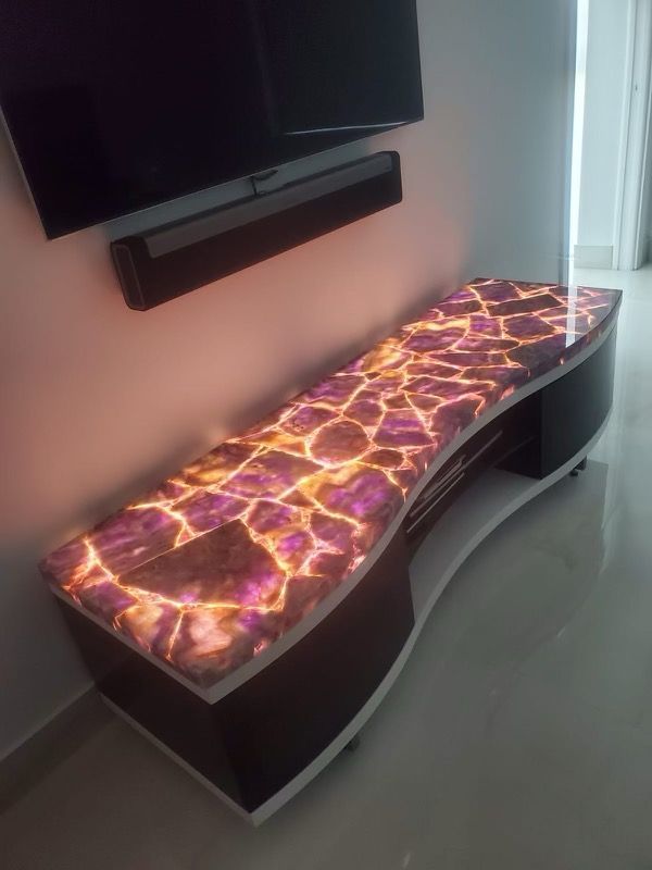 A tv stand with a purple top is sitting in a living room next to a wall mounted tv.