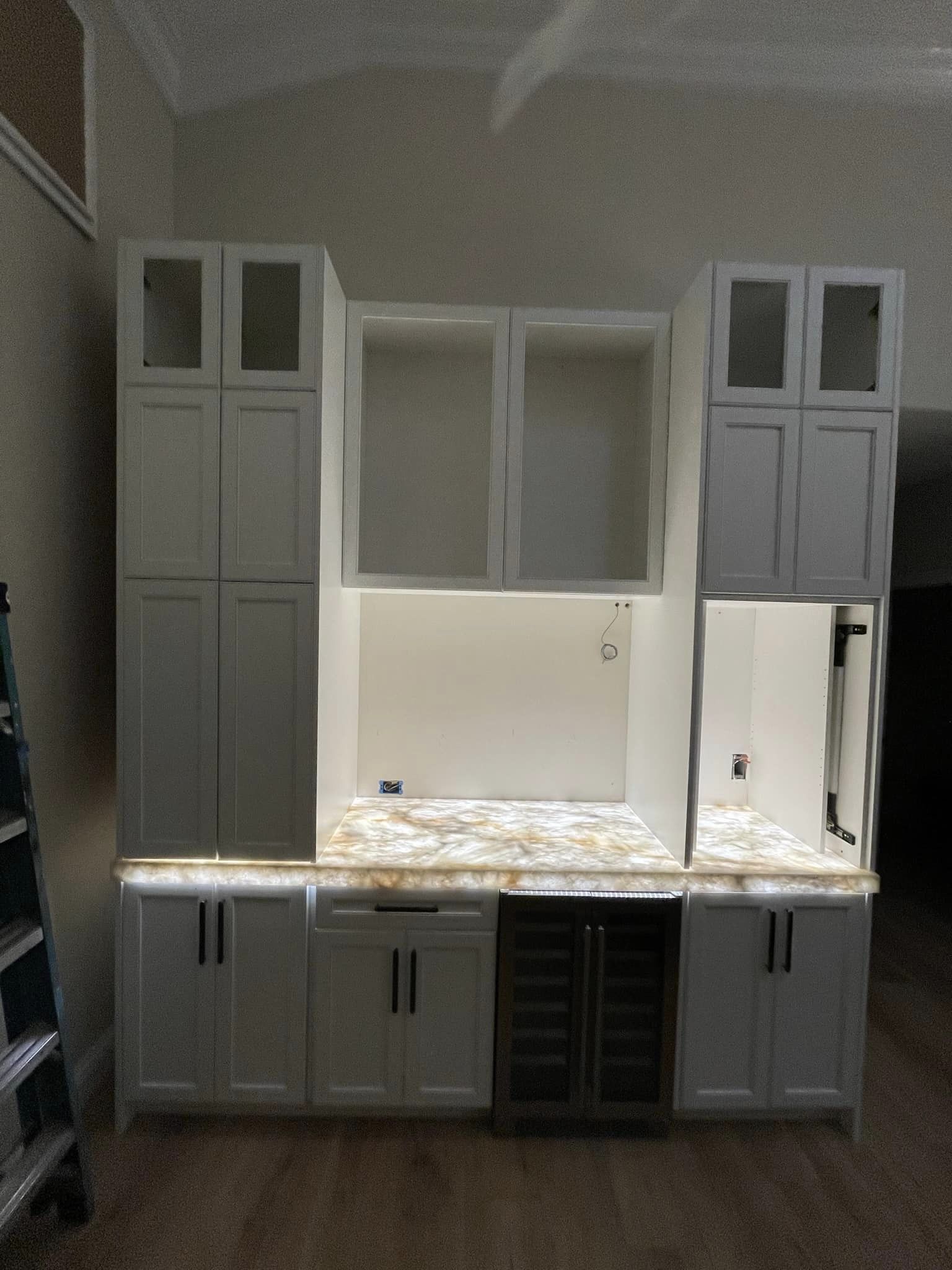 A kitchen with white cabinets and a wine cooler