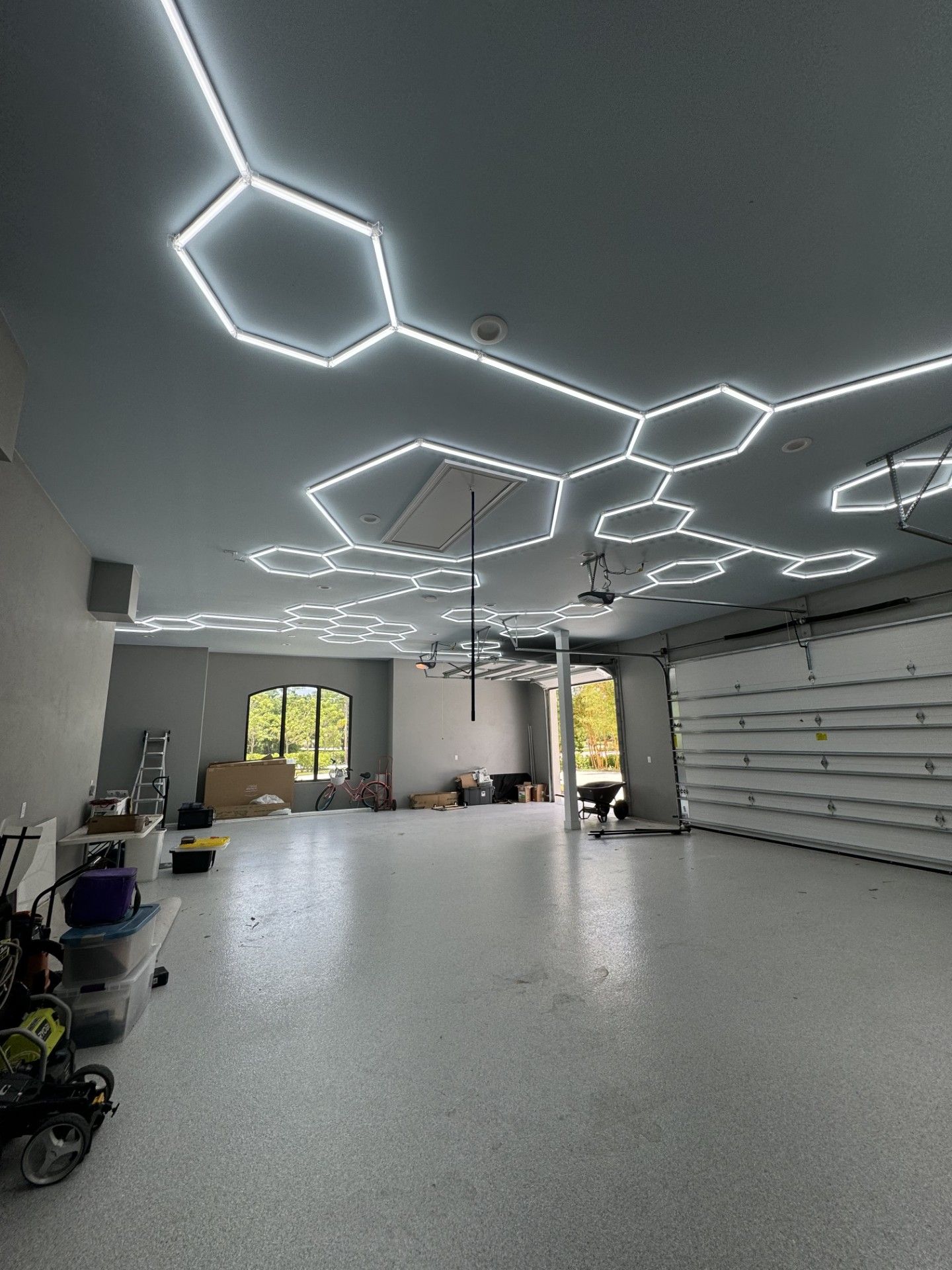 Modern, empty room with geometric ceiling lights and a large garage door. 