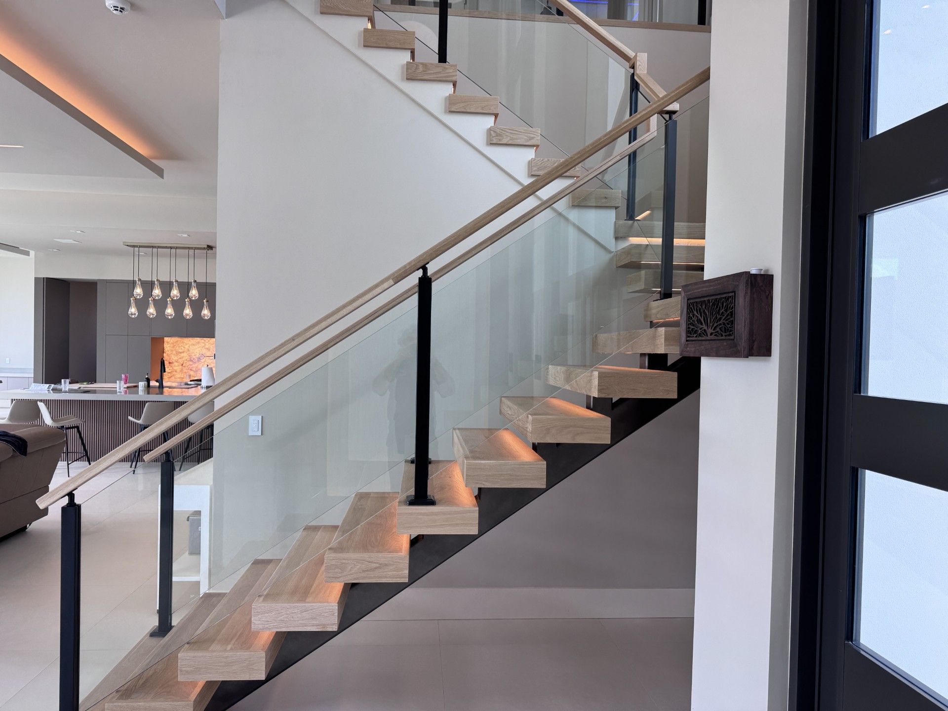 Modern staircase with wood steps, glass panels, and black metal accents. 