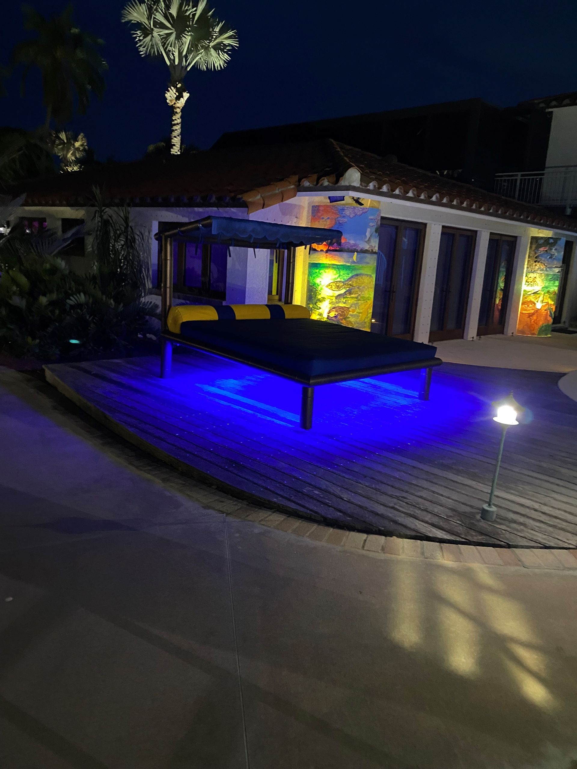 A large bed is lit up with blue lights in front of a house.