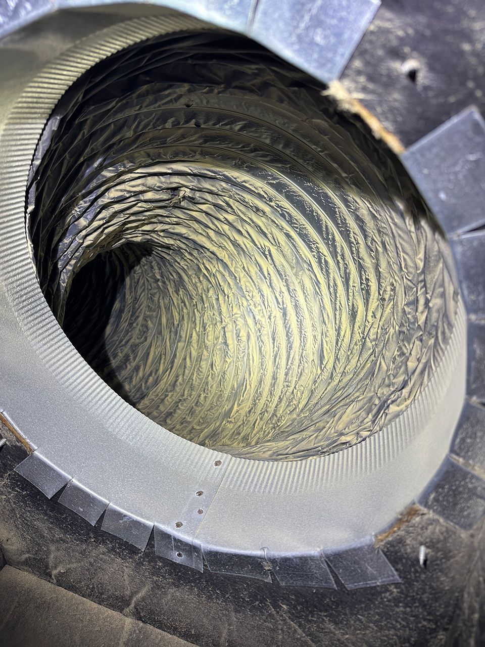 A close up of a dirty air duct with a hole in the middle