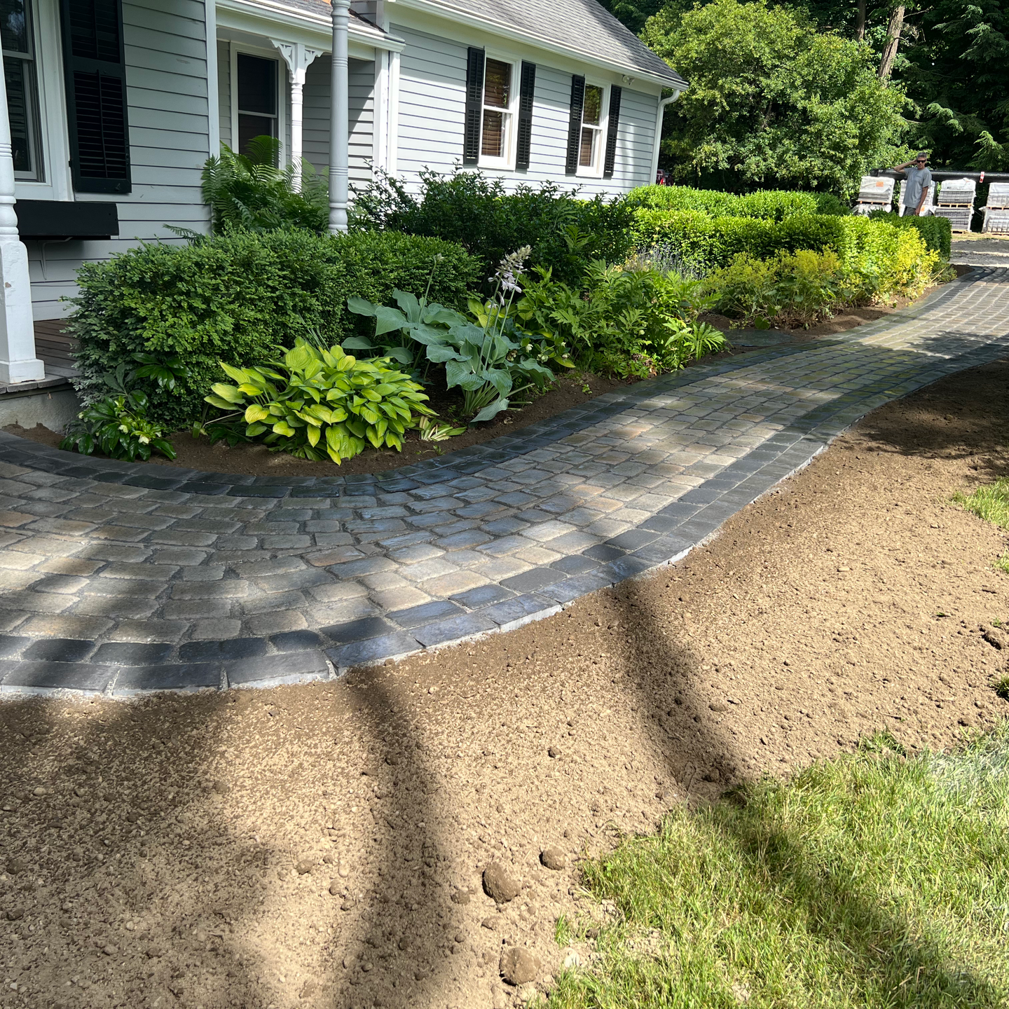 A brick walkway leading to a white house