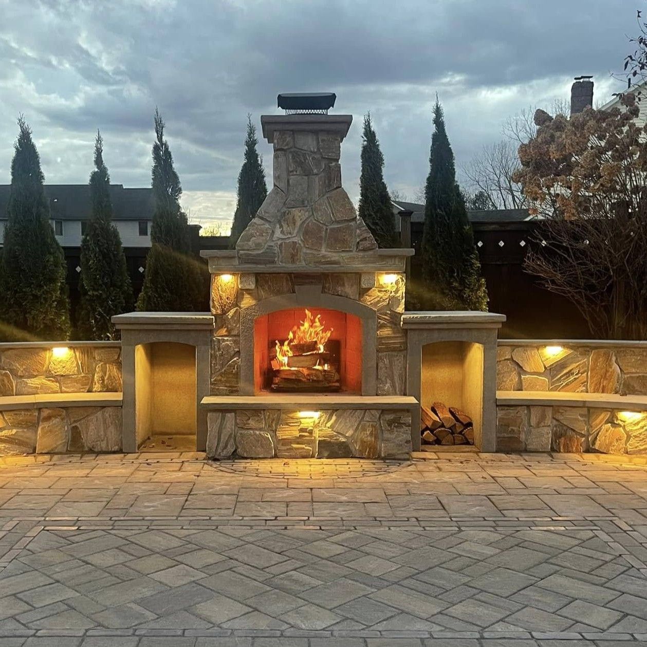 A large stone fireplace is lit up at night