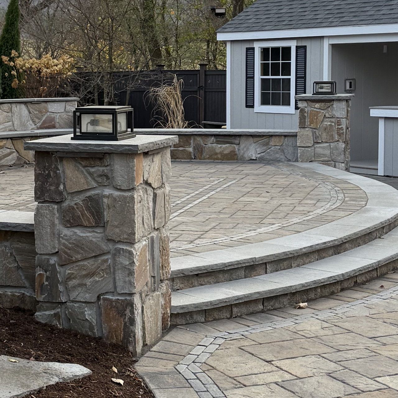 A stone patio with steps and a shed in the background
