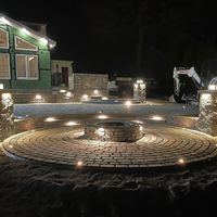 A fire pit is lit up at night in front of a house
