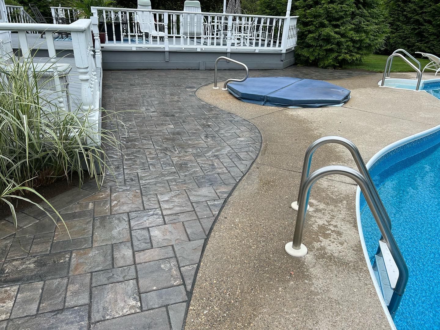 A swimming pool with a walkway leading to it and a hot tub.