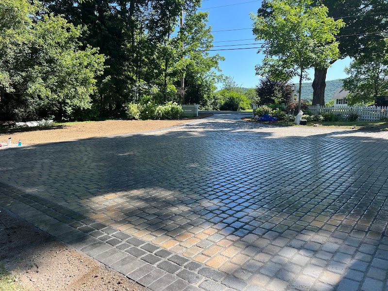 A brick driveway with trees on the side of it
