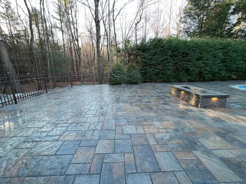 A patio with a fence and trees in the background.