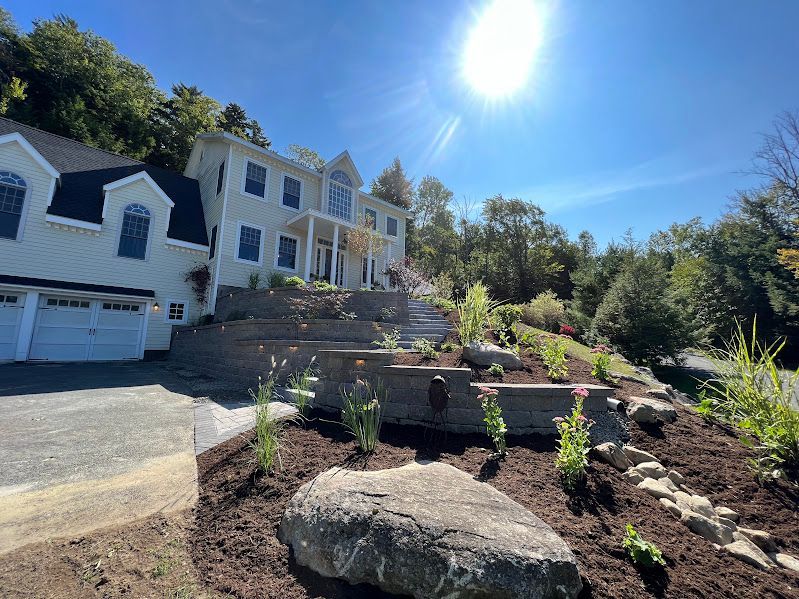 A large white house is sitting on top of a hill surrounded by trees.