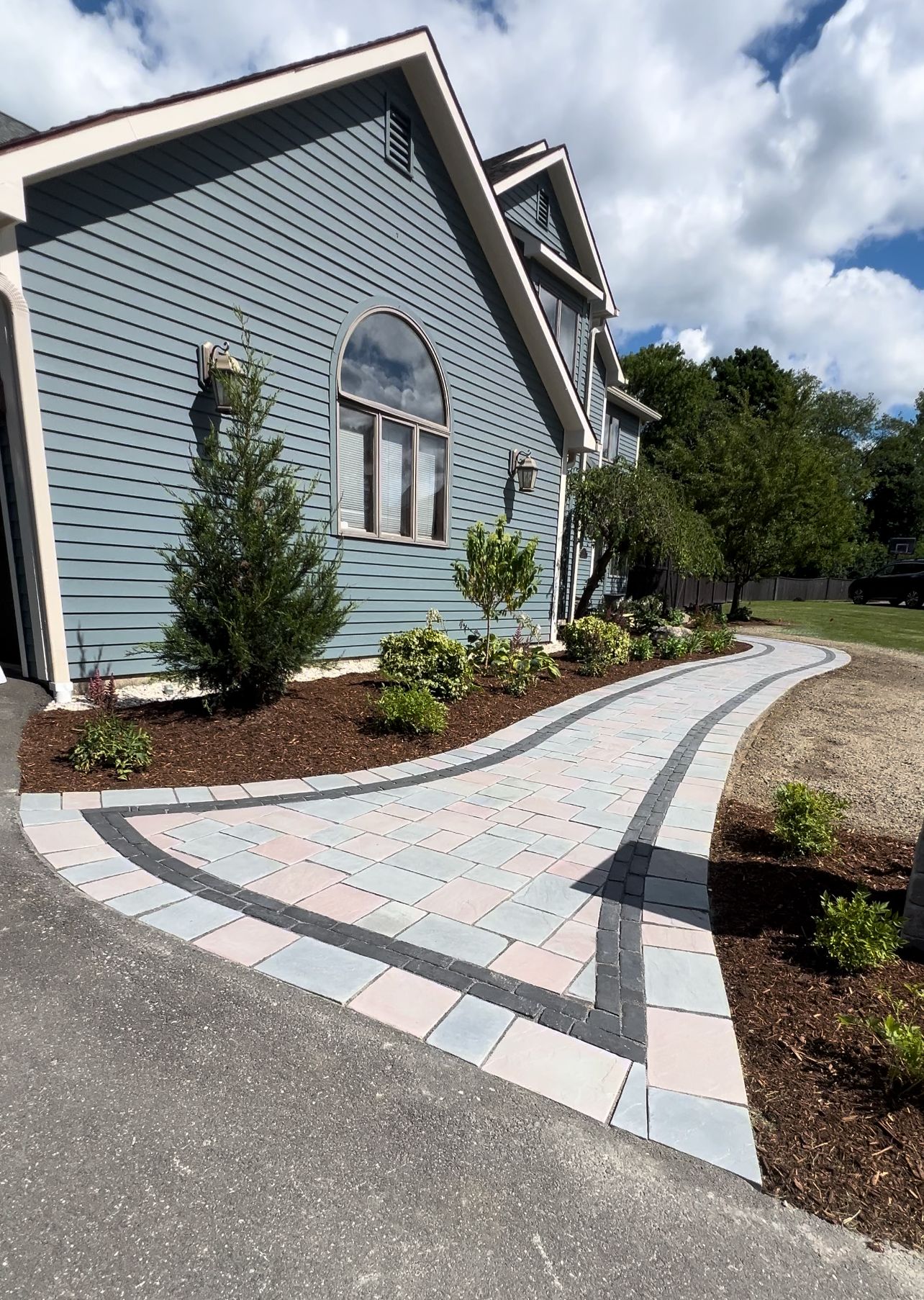 A blue house with a brick walkway leading to it.