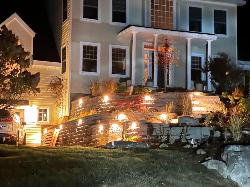 A house is lit up at night with a car parked in front of it.