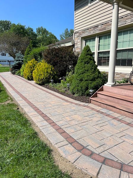 A brick walkway leading to a house with a porch and steps.
