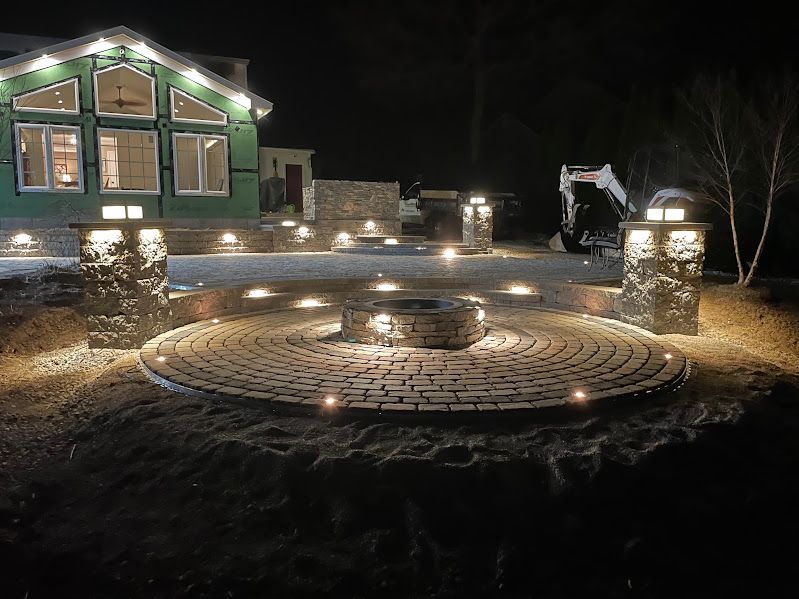 A house with a fire pit in front of it is lit up at night.