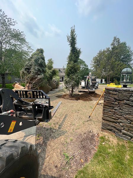 A tractor is driving down a dirt road next to a stone wall.