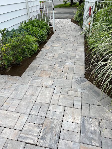 A brick walkway leading to a house with a gate.