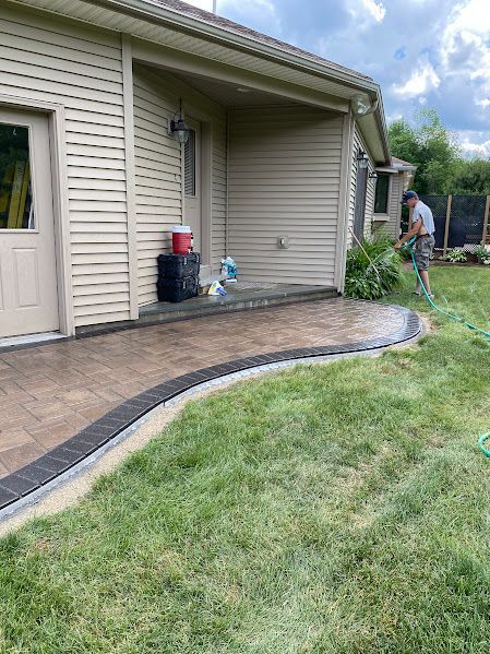 A man is watering a lawn with a hose in front of a house.