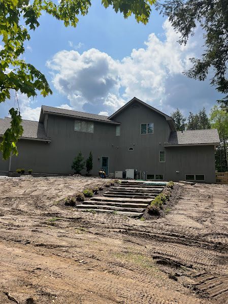 A large house is sitting on top of a dirt field.