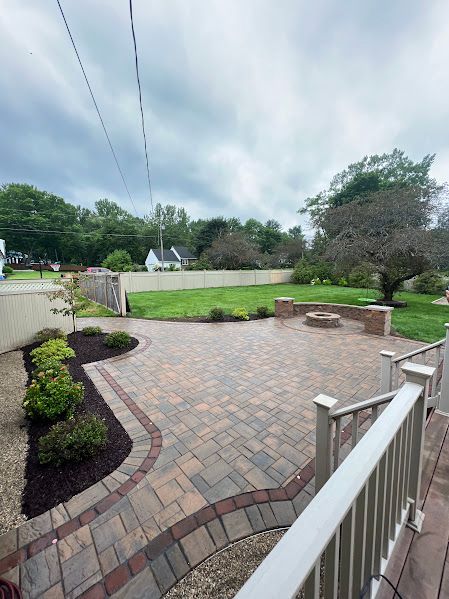 A patio with a fire pit in the middle of it and a white railing.