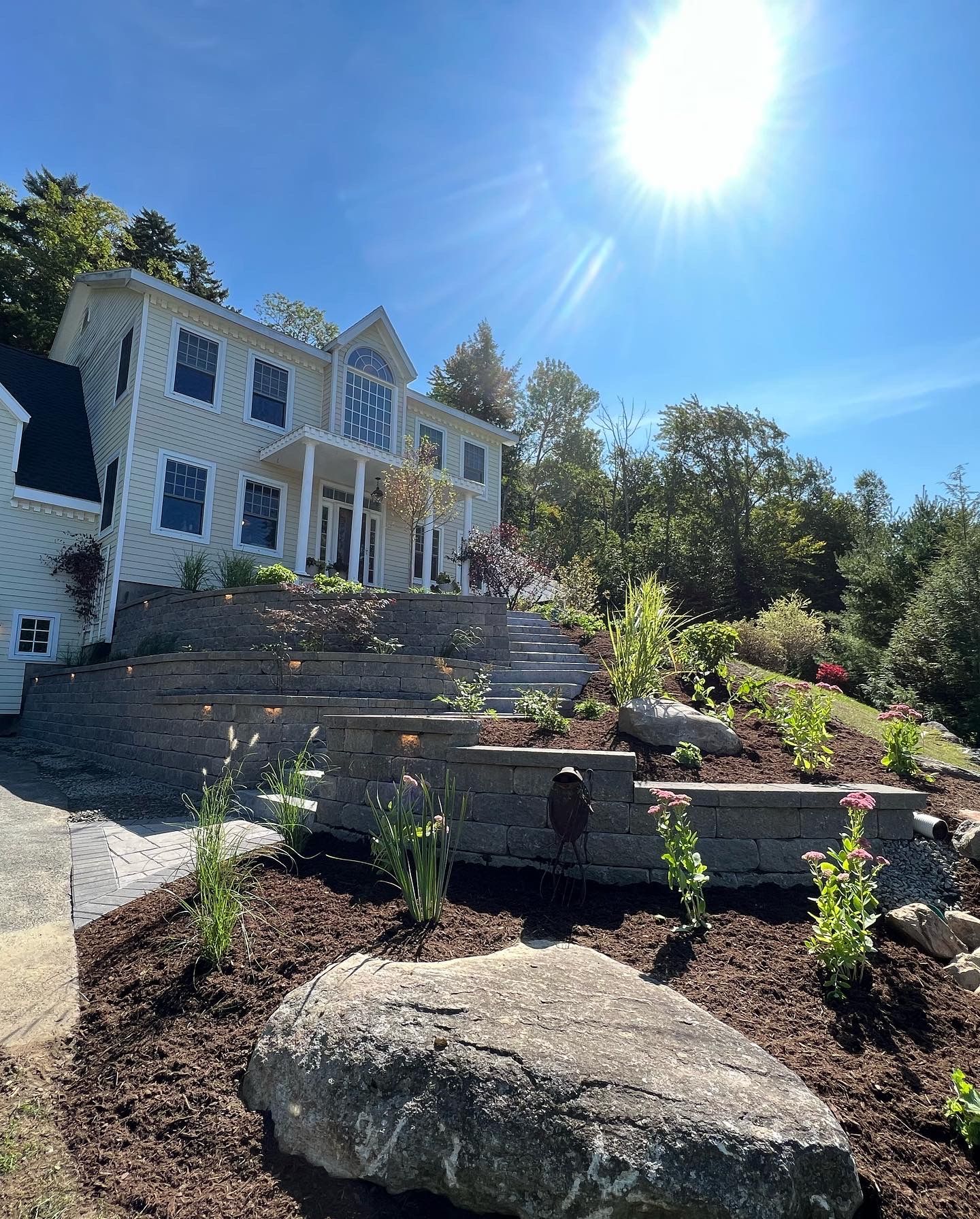 A large white house is sitting on top of a hill surrounded by trees.