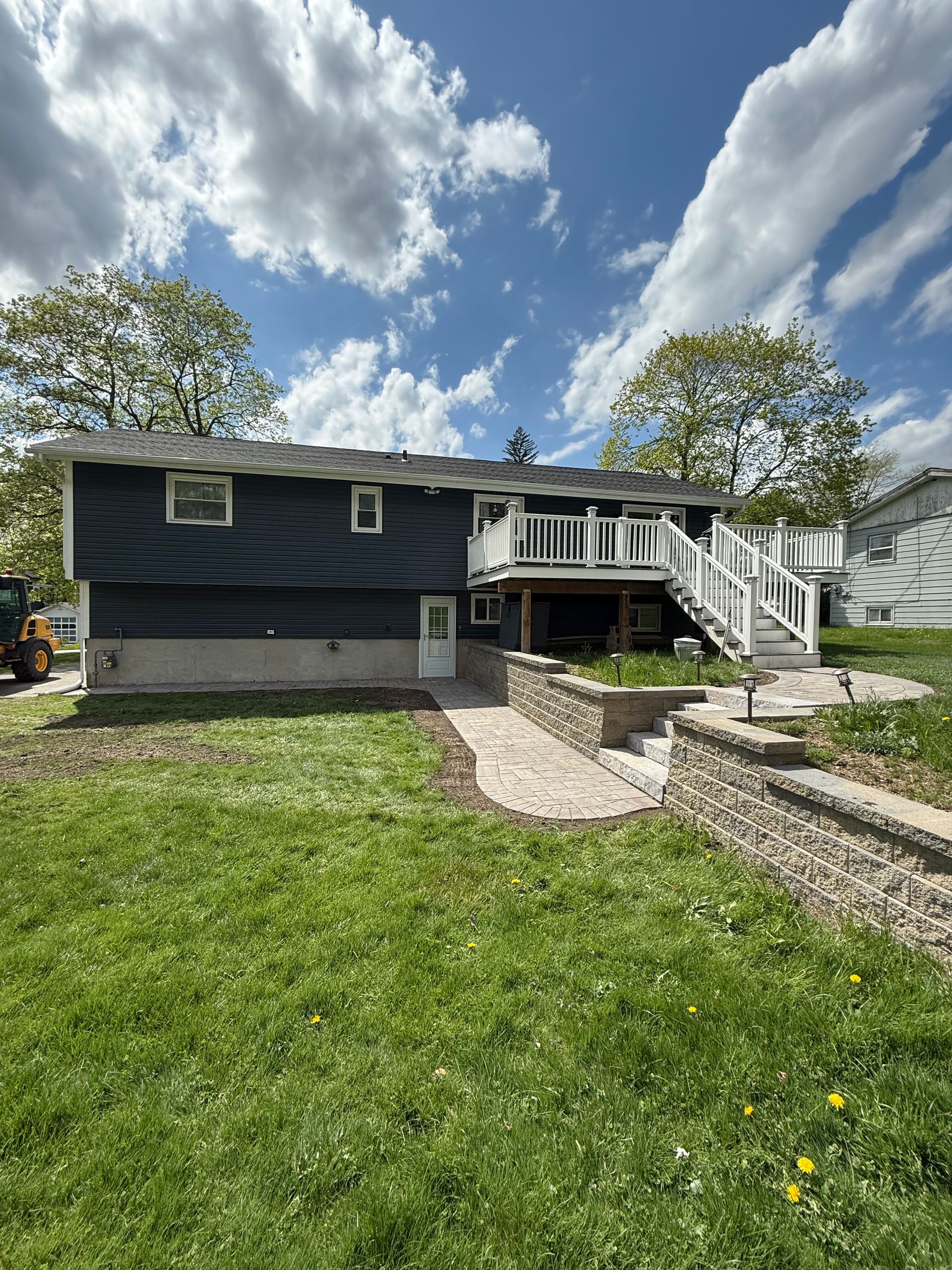 A stone walkway leading to a grassy field next to a stone wall.