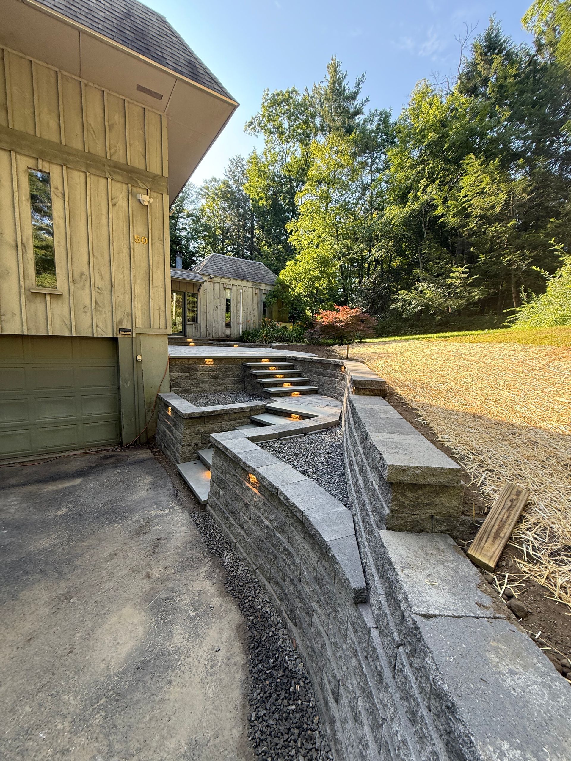 A stream of rocks is running through a garden in front of a house.