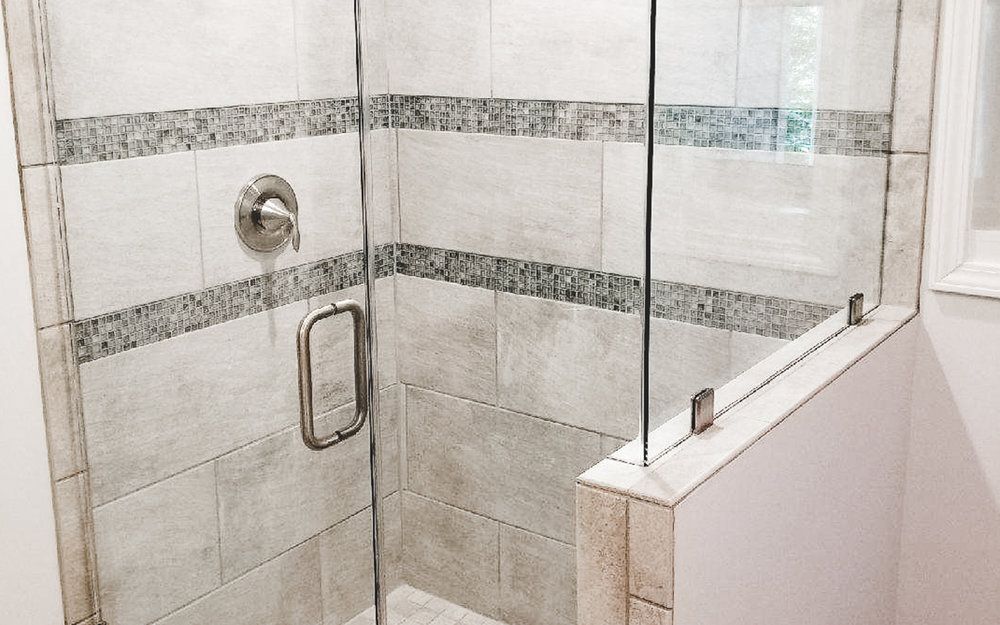 A bathroom with a walk in shower with a glass door.