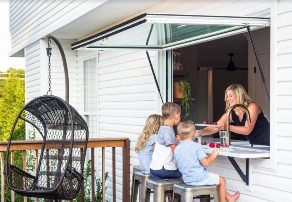 A woman and three children are sitting at a table in front of a window.