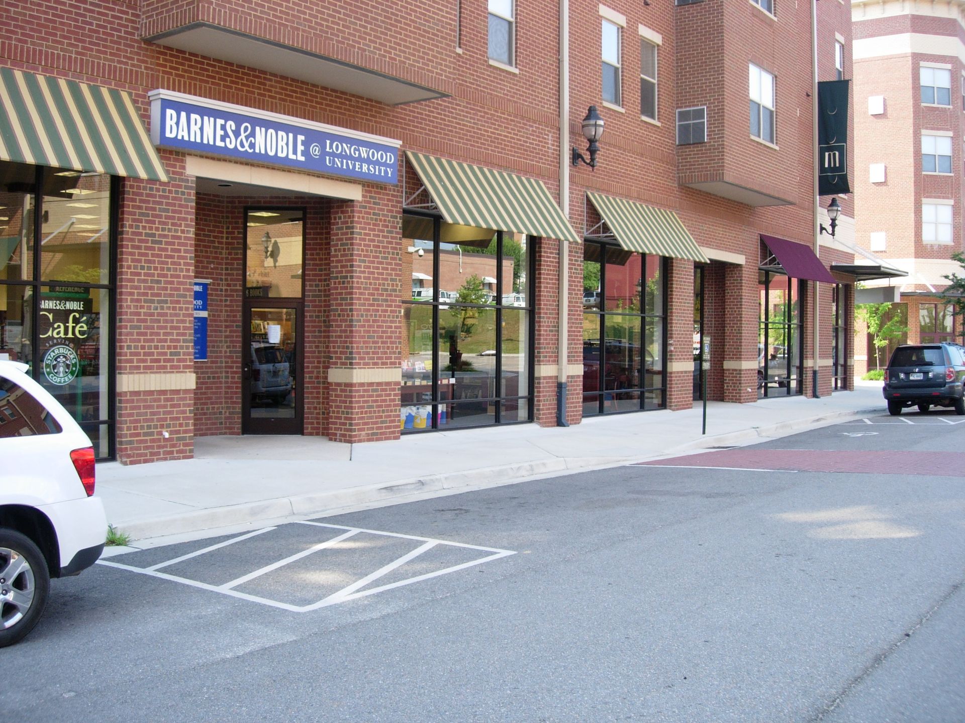 A white car is parked in front of a barnes & noble store