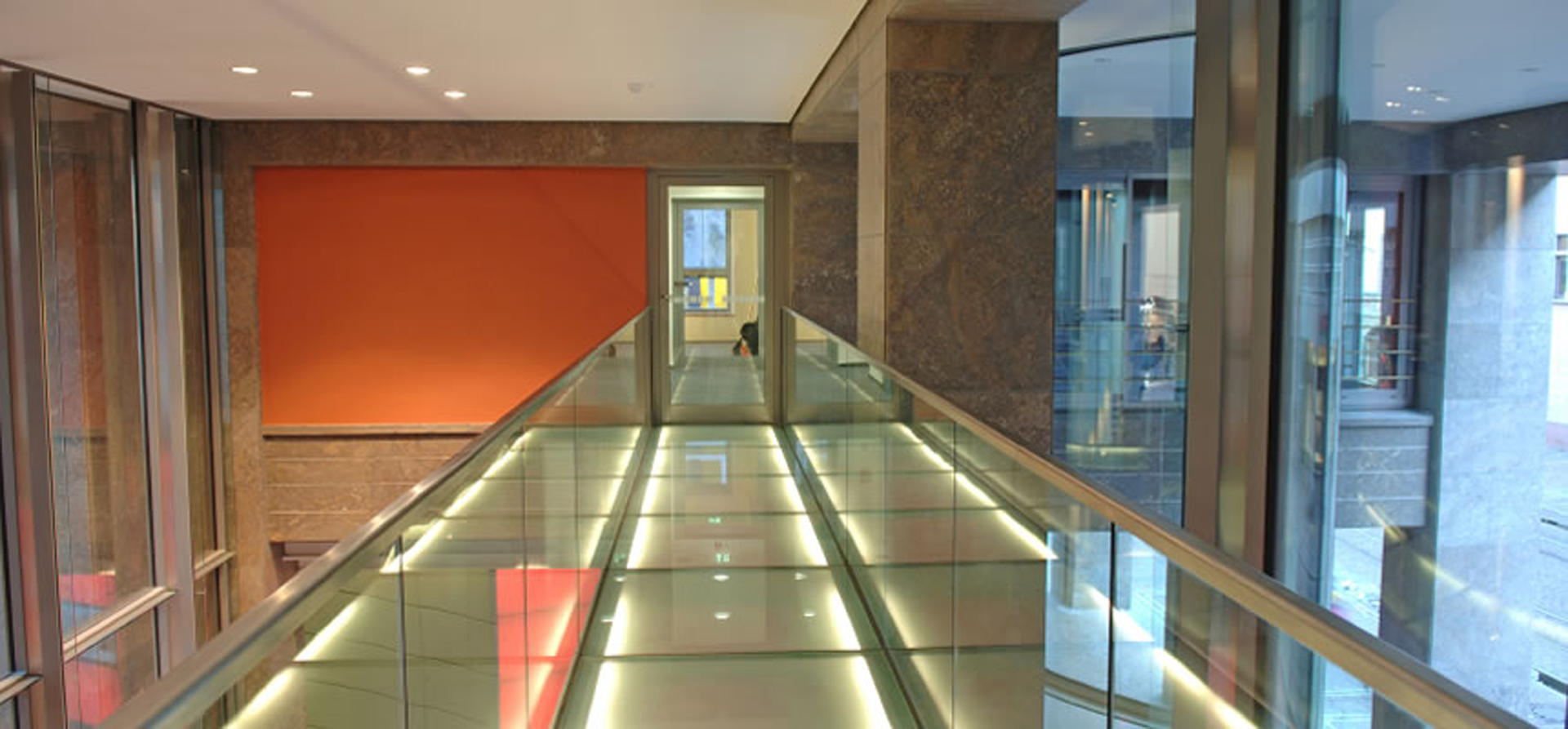 A hallway with a glass railing and a red wall