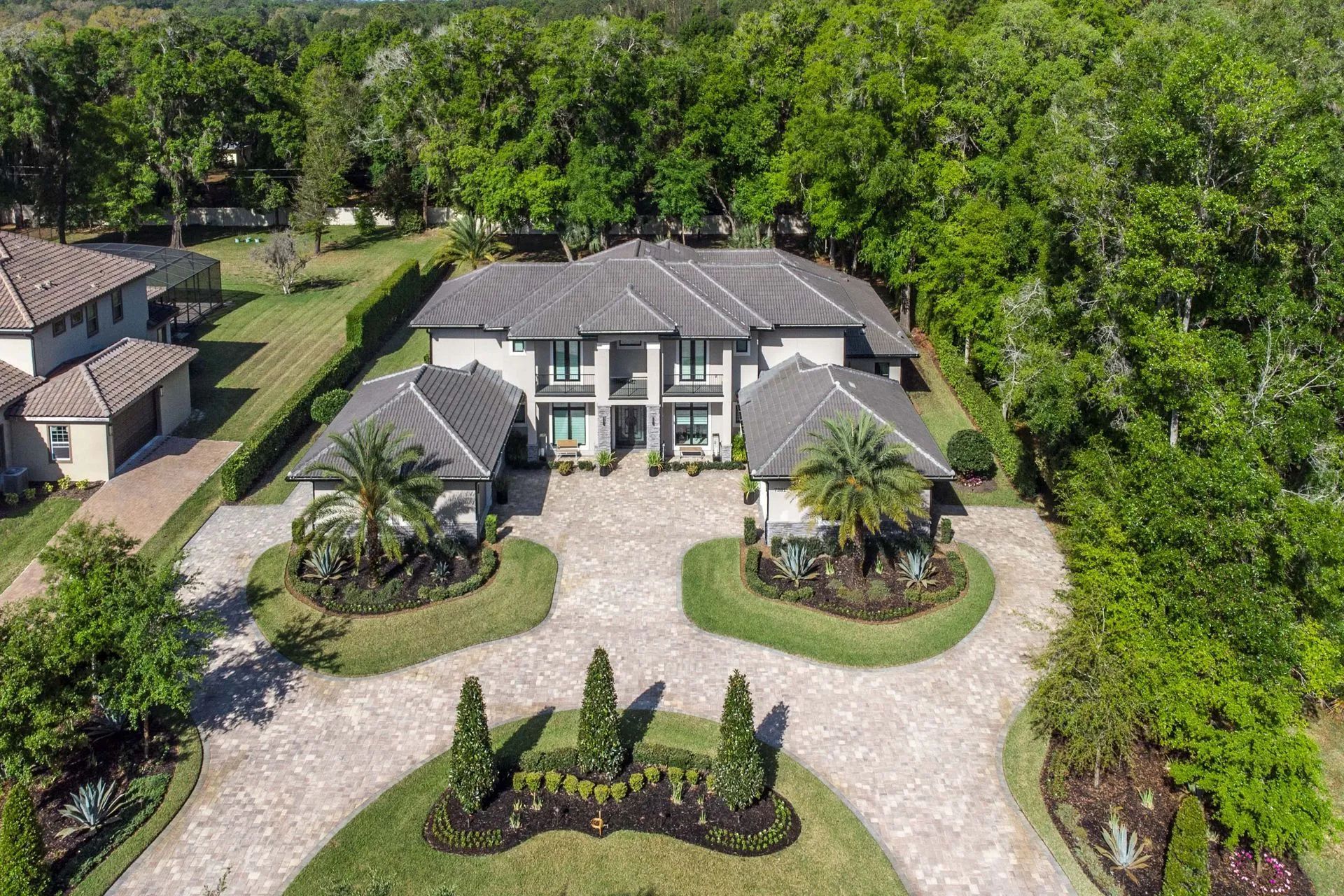 An aerial view of a large house with a driveway surrounded by trees.
