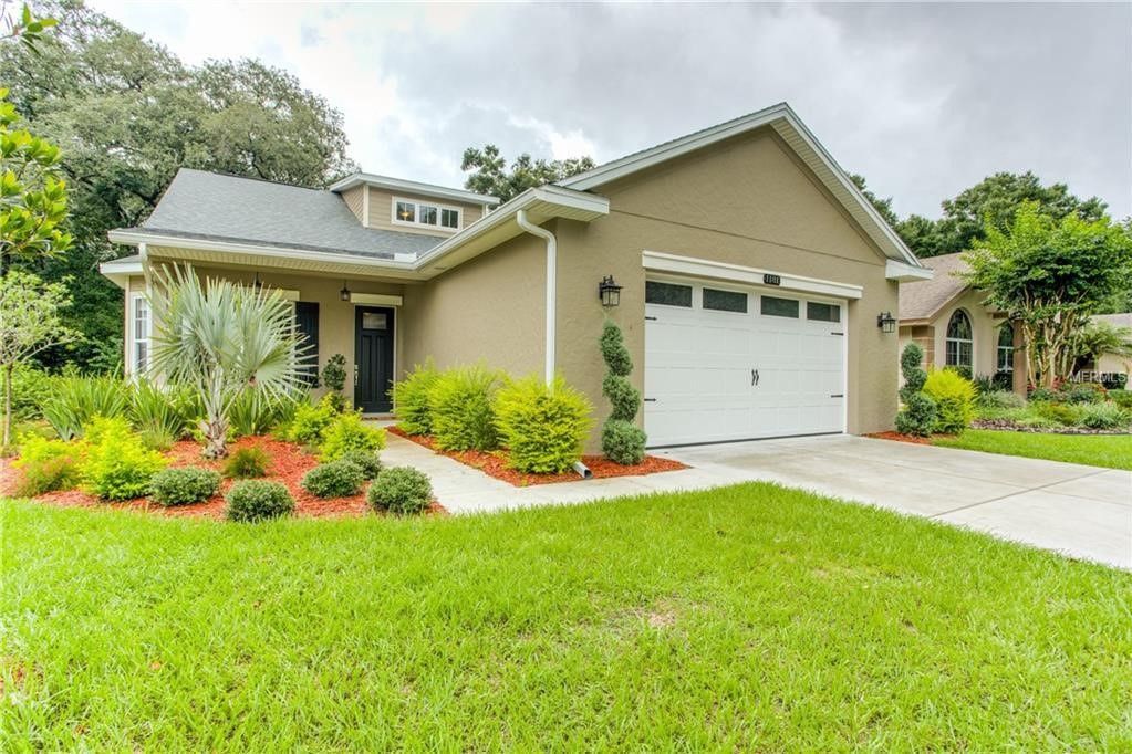 A house with a white garage door and a large lawn in front of it