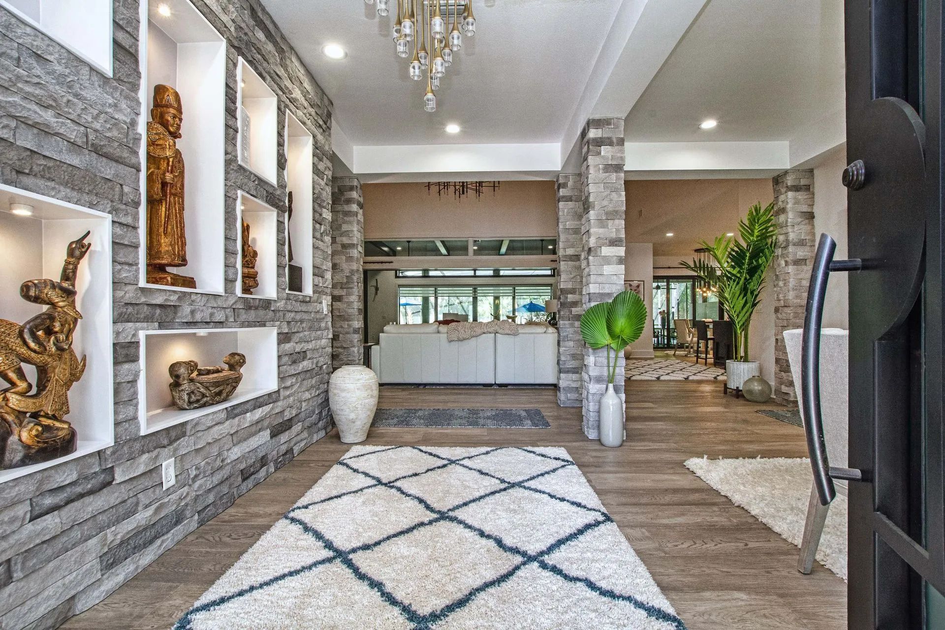 A hallway in a house with a rug and a brick wall.