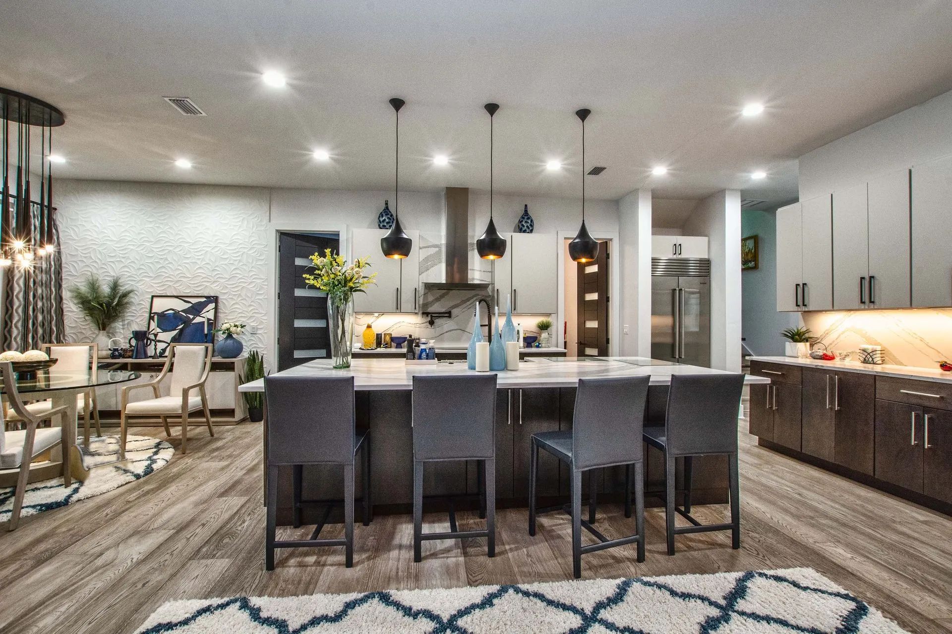 A kitchen with a large island and stools in a house.