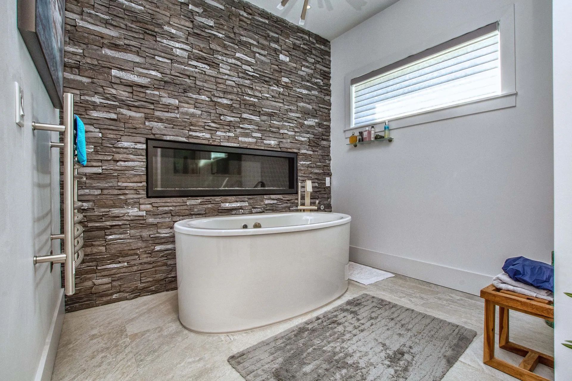 A bathroom with a tub and a stone wall.