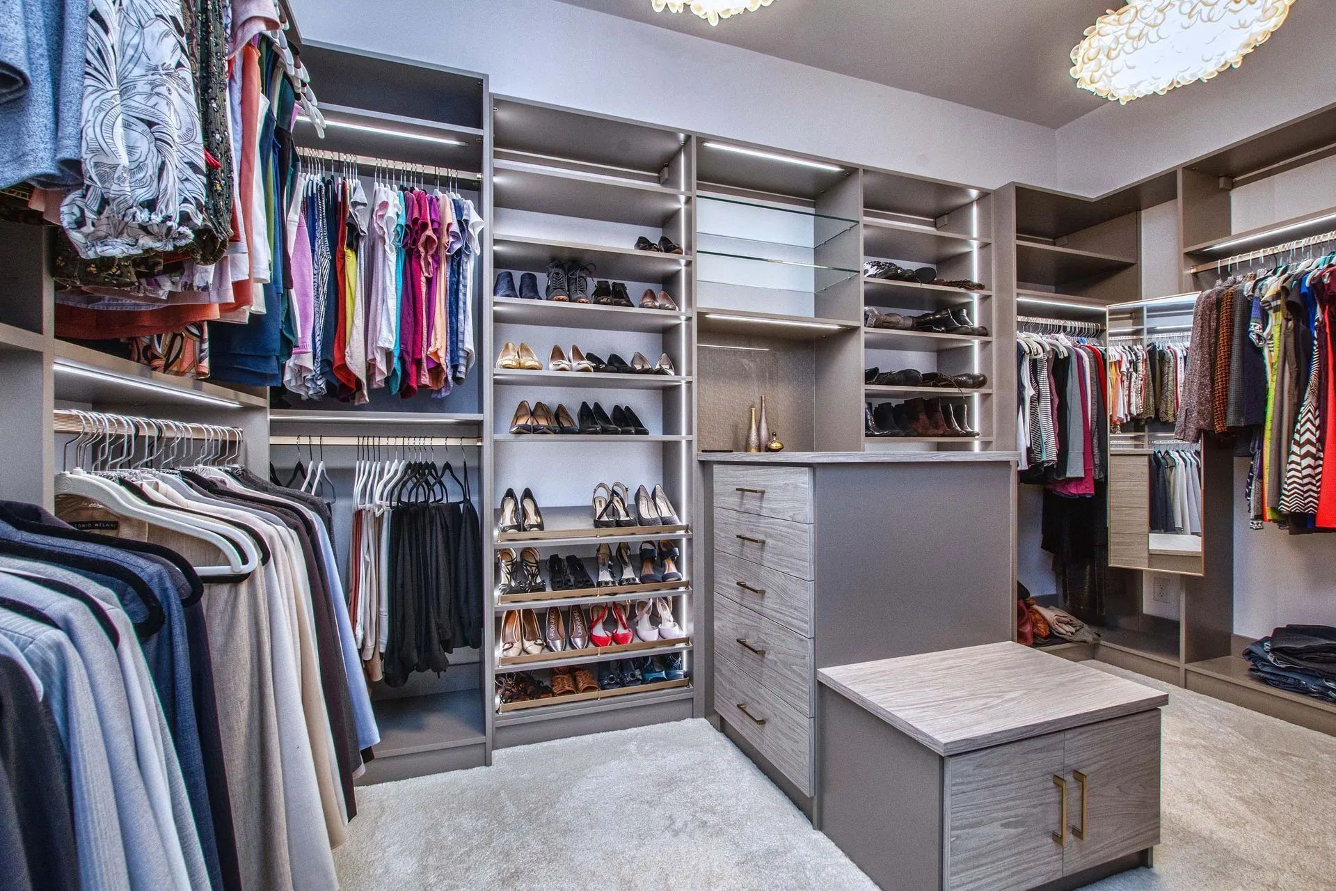 A walk in closet filled with lots of clothes and shoes.