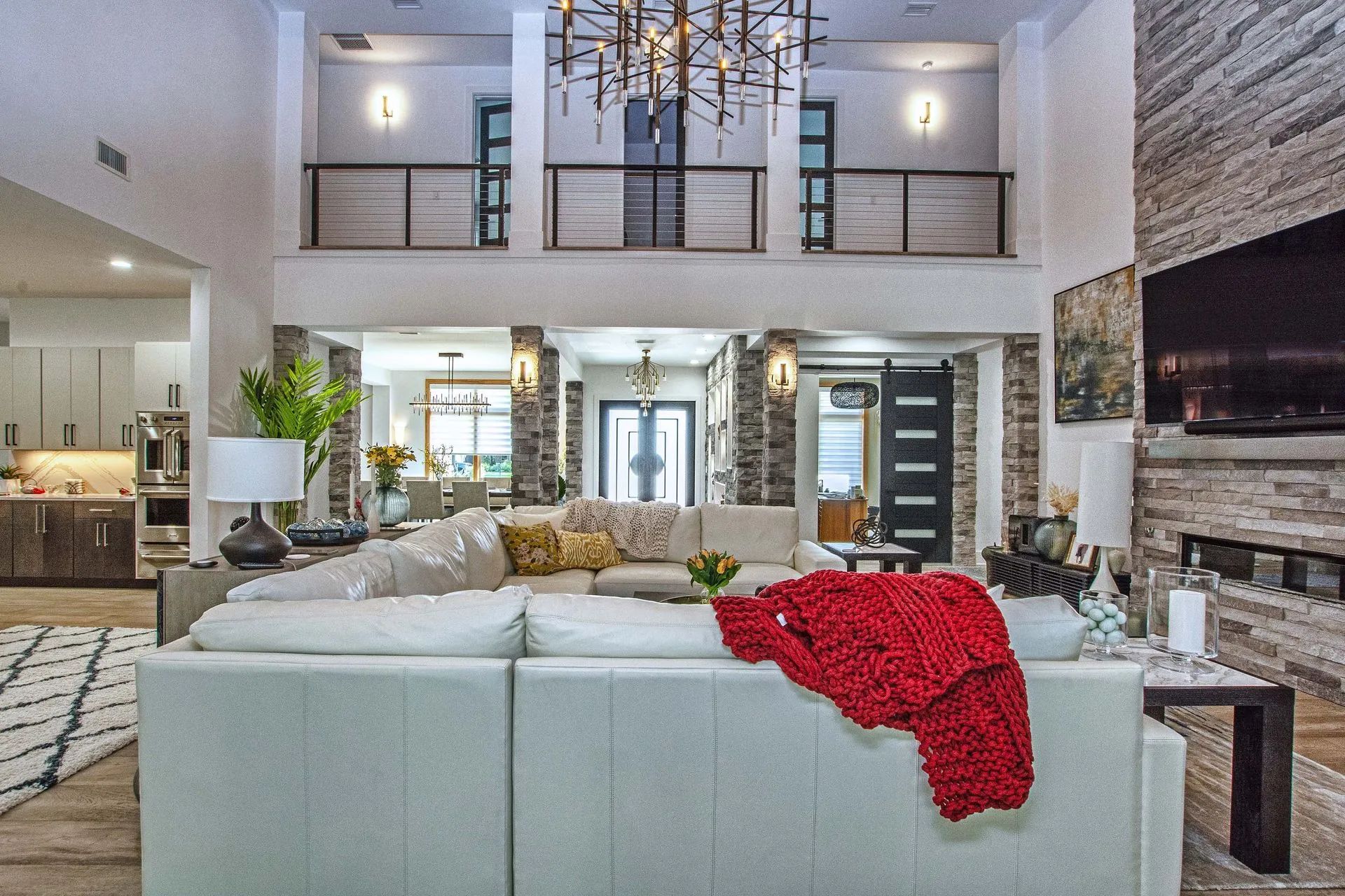A living room with a white sectional couch and a red blanket on it.