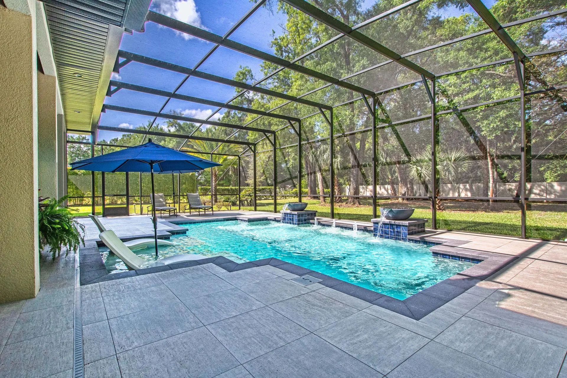 A large swimming pool with a screened in area and a blue umbrella.