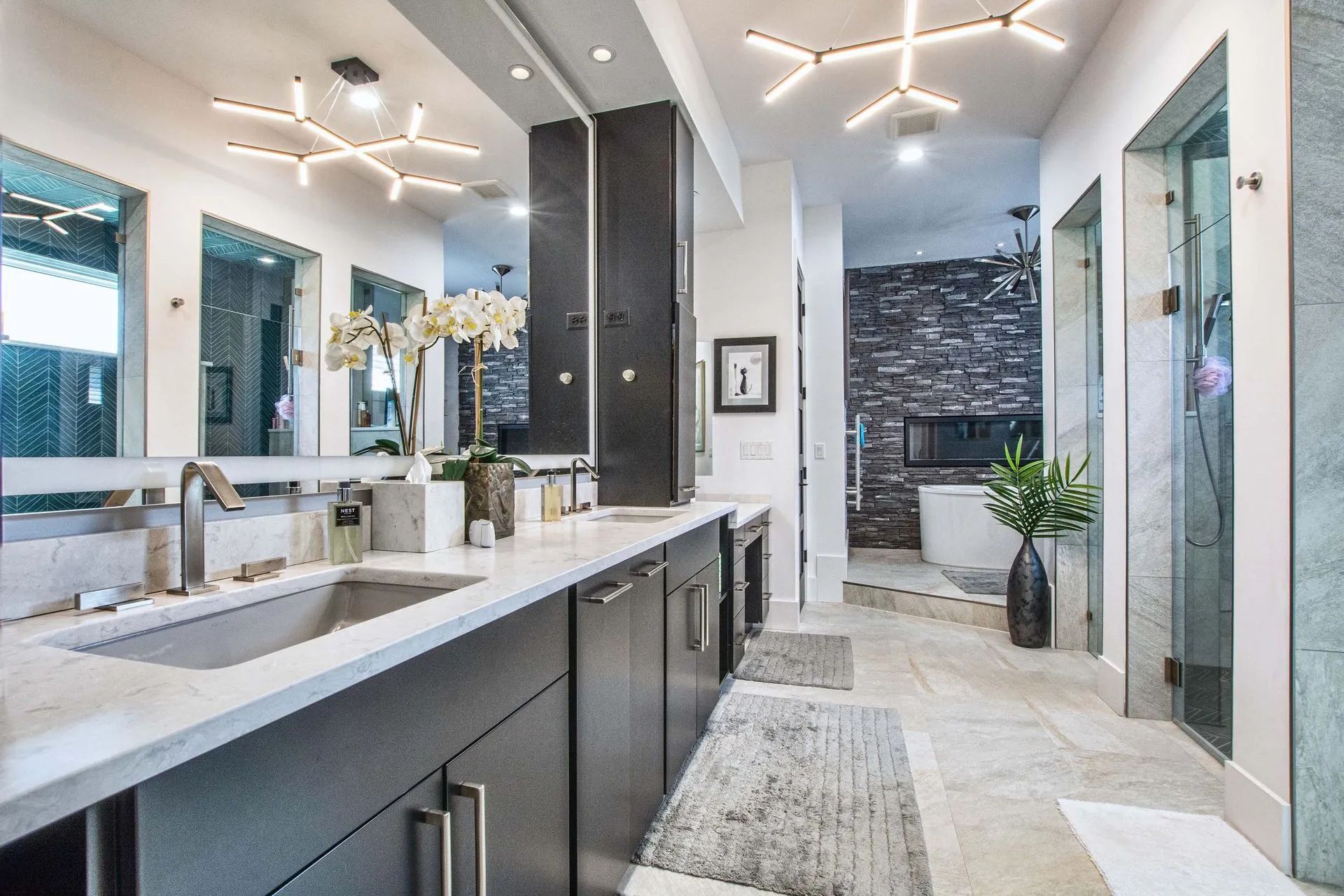 A bathroom with a sink, mirrors, and a walk-in shower.