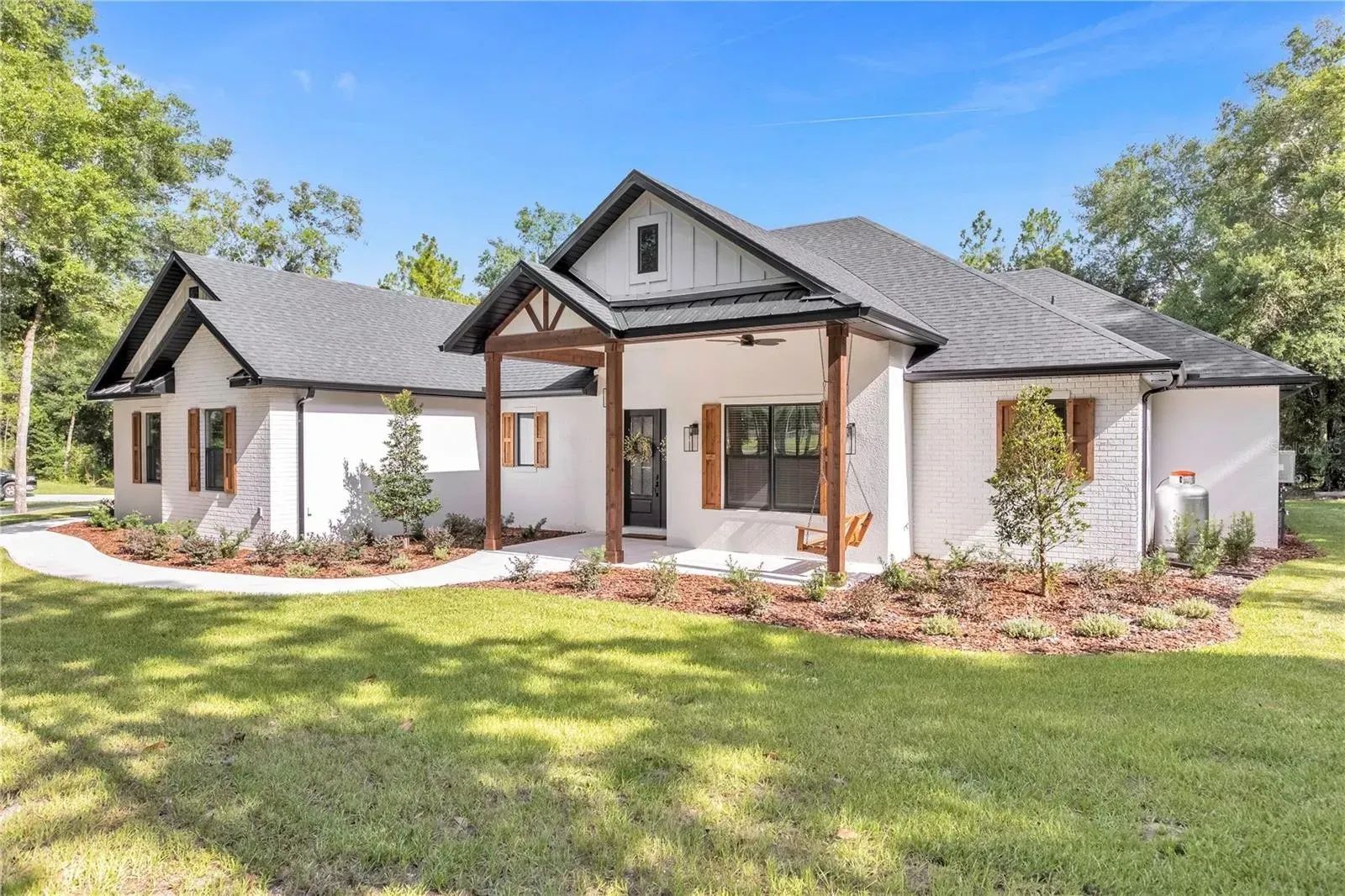 A white house with a black roof is sitting on top of a lush green field.