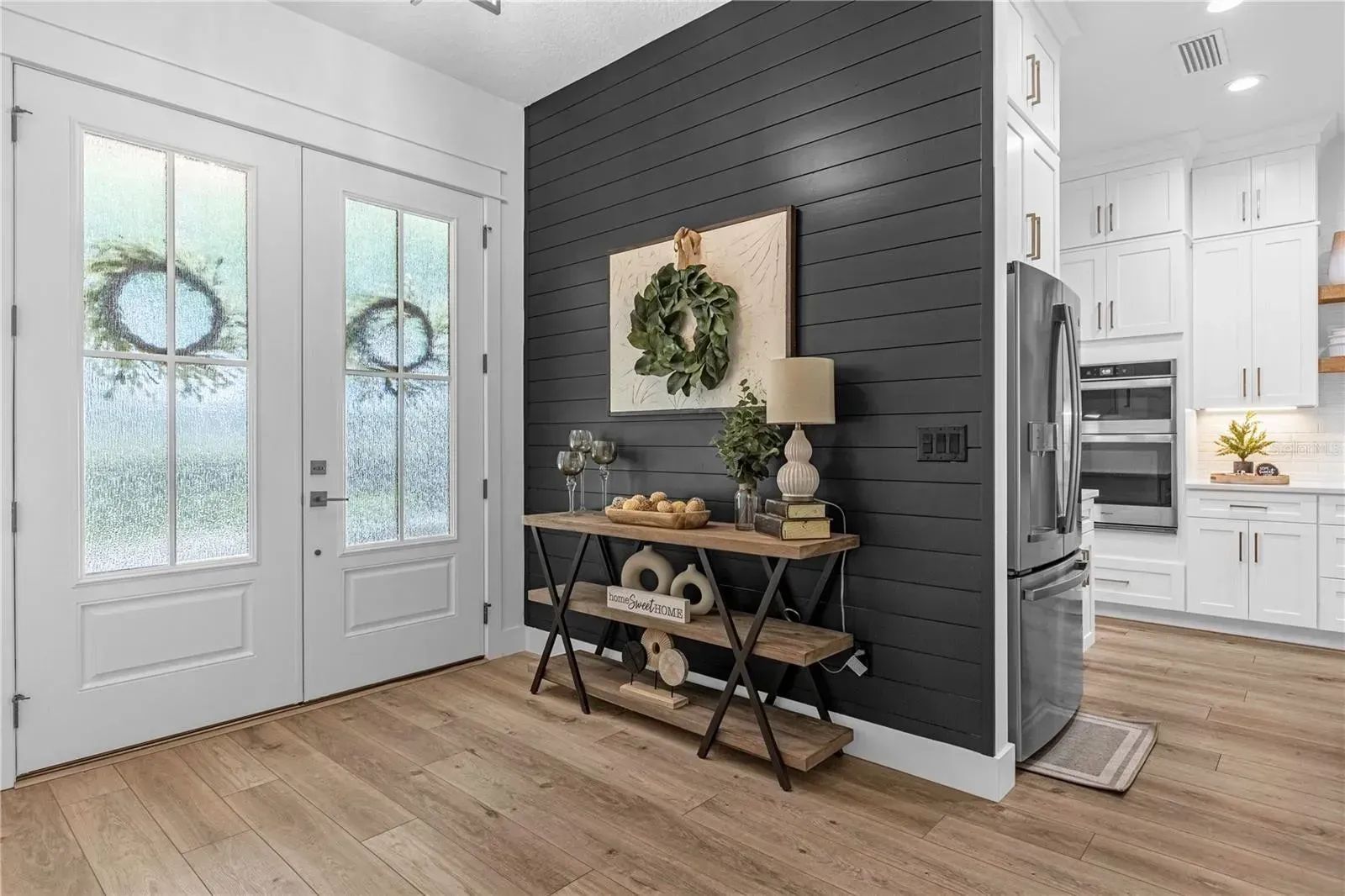 A hallway with a table and a refrigerator in a house.