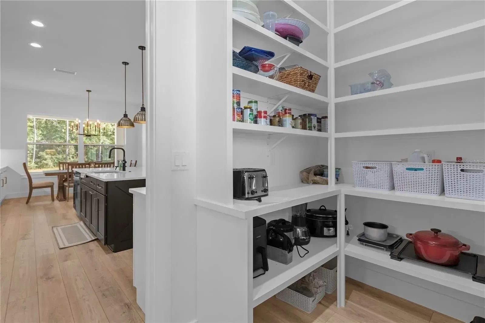 A pantry in a kitchen with lots of shelves and pots and pans.