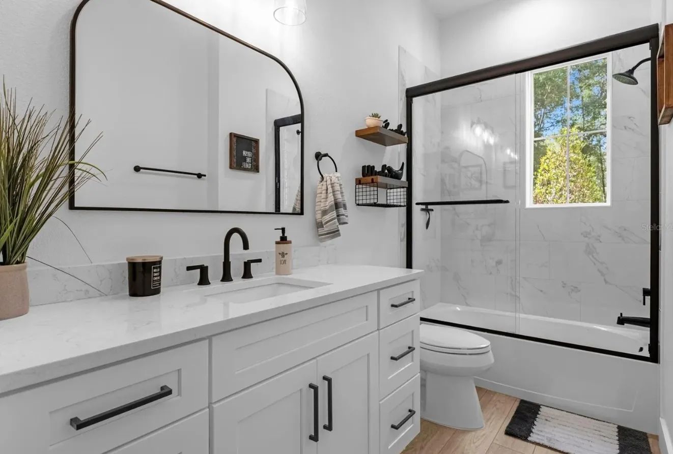 A bathroom with a sink, toilet, tub, and mirror.