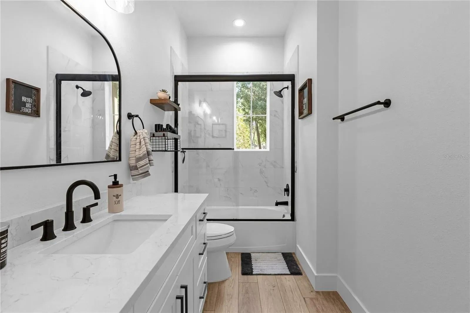 A bathroom with a sink, toilet, shower, and mirror.