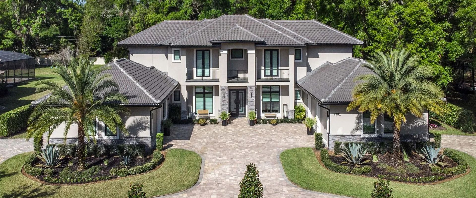 An aerial view of a large house with palm trees in front of it.